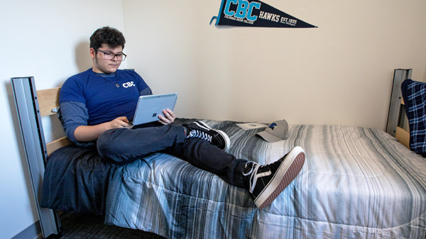 Student sitting on bed using a laptop